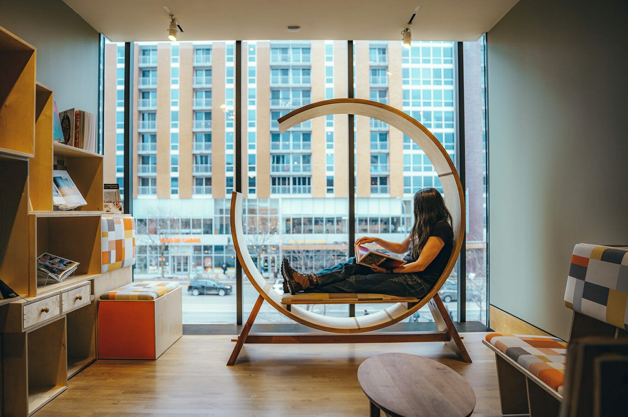 Woman looks through a book seated in circular lounge chair at the Chazen Museum of Art